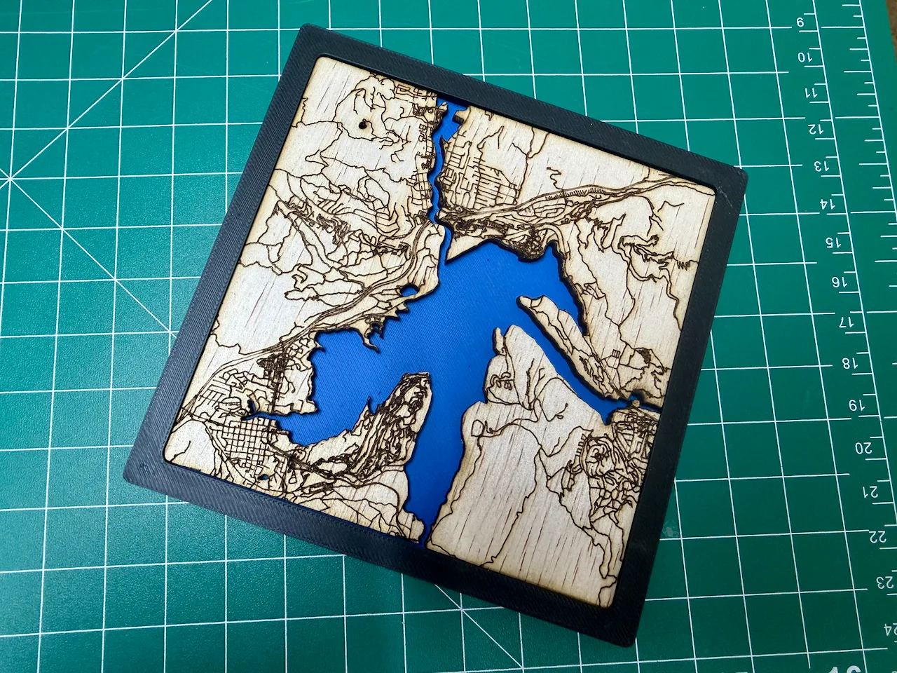 Wooden coastal map with blue acrylic water in a black printed frame